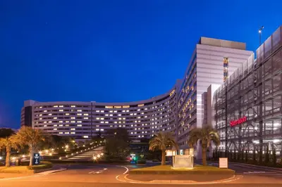 a large building with palm trees in front of it at Sheraton Grande Tokyo Bay Hotel in Urayasu