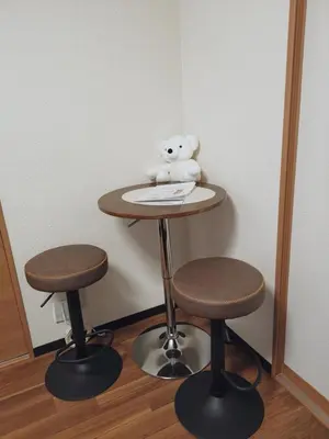 a teddy bear sitting on a table with two stools at Sun Hotel in Tokyo