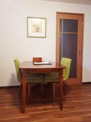 a wooden table with two green chairs in a room at Sun Hotel in Tokyo