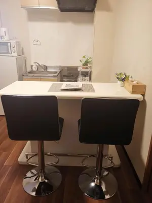 a kitchen with two bar stools in front of a counter at Sun Hotel in Tokyo