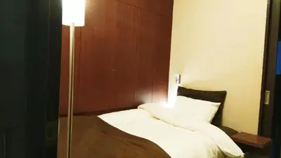 a bedroom with a bed with white sheets and a lamp at Sun Hotel in Tokyo