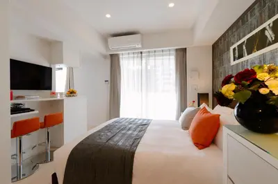 a hotel room with a bed and a vase of flowers at Oakwood Apartments Minami Azabu Tokyo in Tokyo