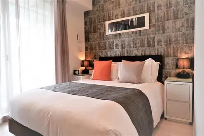 a bedroom with a large bed and a brick wall at Oakwood Apartments Minami Azabu Tokyo in Tokyo