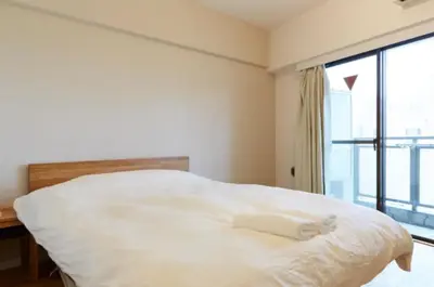 a white bed in a room with a large window at Dwell Urban 7A in Tokyo