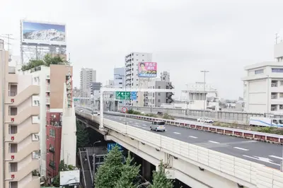a bridge over a highway in a city with buildings at Dwell Urban 7B in Tokyo