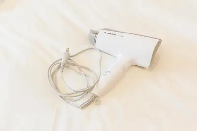 a white hair dryer sitting on top of a bed at Dwell Urban 7B in Tokyo