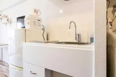 a white kitchen with a sink and a refrigerator at Dwell Urban 6D in Tokyo
