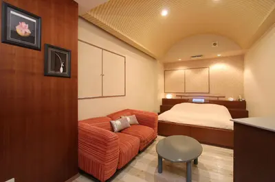 a living room with a couch and a bed at HOTEL DCUBE in Tokyo