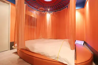 an orange canopy bed in a room with a ceiling at HOTEL DCUBE in Tokyo