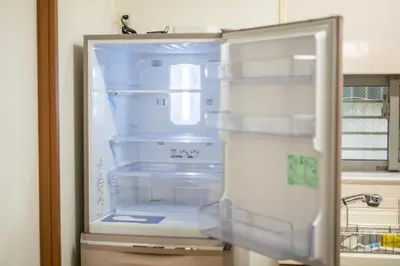 an empty refrigerator with its door open in a kitchen at Yotsuya 110 in Tokyo