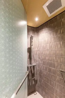 a bathroom with a shower and a tiled wall at cyashitsu ryokan asakusa in Tokyo