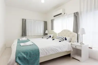 a white bedroom with a large bed with a blue blanket at Gracias Arakawa - Great Access to UENO & ASAKUSA area in Tokyo