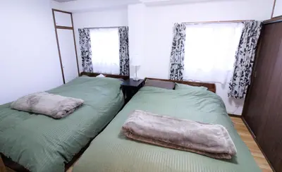 two beds in a bedroom with green sheets at Central Field 5-6F in Tokyo