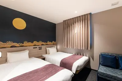 a hotel room with two beds and a chair at La'gent Hotel Shinjuku Kabukicho in Tokyo