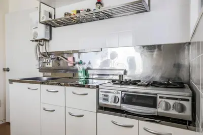 a kitchen with a stove and white cabinets at Jujo Stay Sanyo Mansion in Tokyo