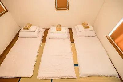 three beds in a room with white sheets at Shinjuku-ku - House / Vacation STAY 3185 in Tokyo
