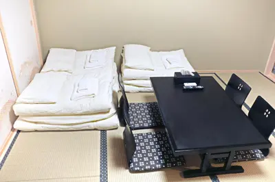 a room with a black table and two beds at Akihabara Nakagawa Inn in Tokyo