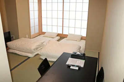 a room with two beds and a table and a window at Akihabara Nakagawa Inn in Tokyo