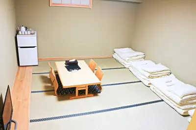 a room with two beds and a table in it at Akihabara Nakagawa Inn in Tokyo