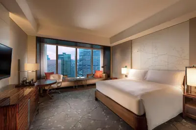 a bedroom with a bed and a desk and a television at Conrad Tokyo in Tokyo