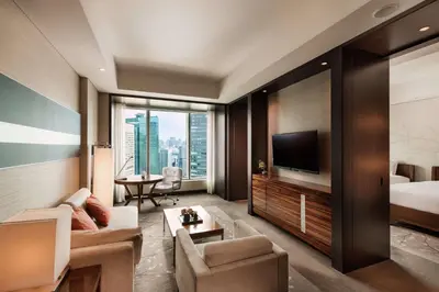 a living room with a couch and a bed and a television at Conrad Tokyo in Tokyo