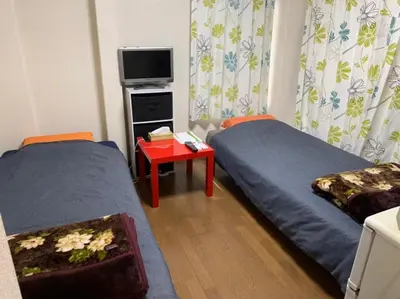 a room with two beds and a table with a tv at Tokyo Stay Ikebukuro in Tokyo