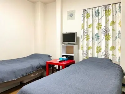 a bedroom with two beds and a tv and a red table at Tokyo Stay Ikebukuro in Tokyo