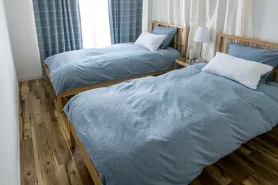 two beds in a bedroom with blue sheets at ZAITO Tokyo Kikukawa Economy Inn \u5b85\u4e1c\u4e1c\u4eac\u83ca\u5ddd\u6c11\u5bbf in Tokyo