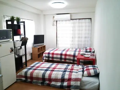 a living room with two beds and a refrigerator at Tokyo Stay Rord Shinjuku in Tokyo