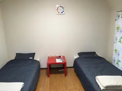 two beds in a room with a table and a clock at Tokyo Stay Rord Shinjuku in Tokyo
