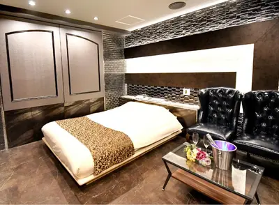 a bedroom with a bed and two black leather chairs at Hotel Gran Villa in Tokyo