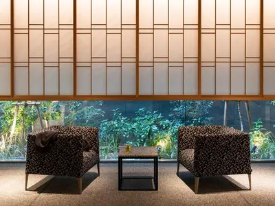 two chairs and a table in front of a large aquarium at Mitsui Garden Hotel Ginza-gochome in Tokyo