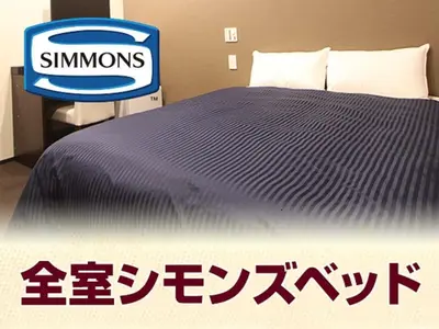 a bed with a blue comforter and a sign next to it at HOTEL LiVEMAX Kayabacho in Tokyo