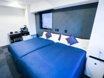 a bedroom with a large blue bed with white pillows at HOTEL LiVEMAX Tokyo Shintomicho in Tokyo