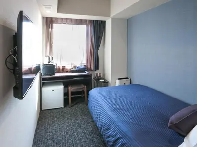 a bedroom with a bed and a desk and a window at HOTEL LiVEMAX Akasaka in Tokyo