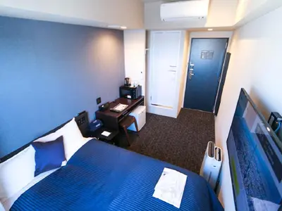 a hotel room with a blue bed and a desk at HOTEL LiVEMAX Akasaka in Tokyo