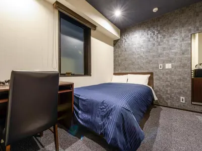 a bedroom with a bed and a desk and a window at HOTEL LiVEMAX Asakusabashi-Ekimae in Tokyo