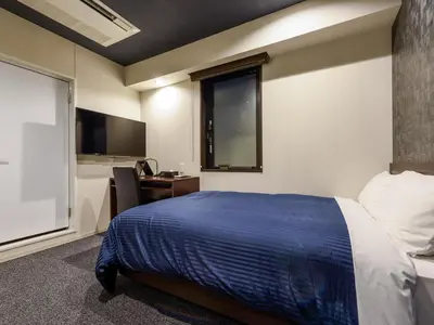 a bedroom with a bed and a desk and a window at HOTEL LiVEMAX Asakusabashi-Ekimae in Tokyo