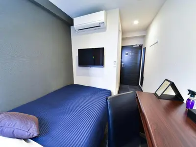 a bedroom with a bed and a desk and a tv at HOTEL LiVEMAX Toyosu-Ekimae in Tokyo