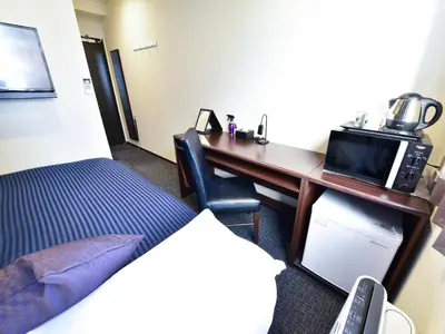 a hotel room with a desk with a bed and a microwave at HOTEL LiVEMAX Toyosu-Ekimae in Tokyo