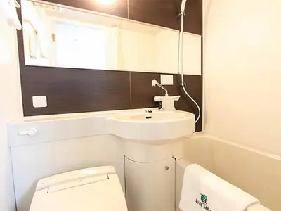 a bathroom with a sink and a toilet and a mirror at HOTEL LiVEMAX Tokyo-Otsuka Ekimae in Tokyo