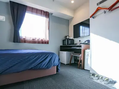 a bedroom with a bed and a desk and a kitchen at HOTEL LiVEMAX Akabane-Ekimae in Tokyo