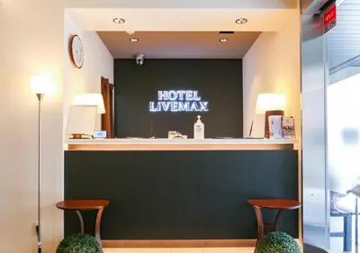 a hotel lobby with two stools and a hotel luxasy sign at HOTEL LiVEMAX Akabane-Ekimae in Tokyo