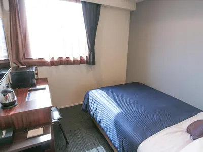 a hotel room with a bed and a desk and a window at HOTEL LiVEMAX Tokyo Ayase-Ekimae in Tokyo