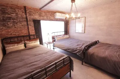 a bedroom with two beds and a brick wall at Shinjuku NY House 1 in Tokyo