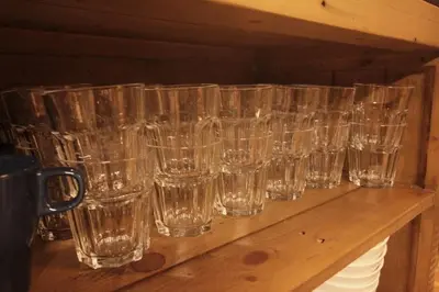 a row of empty glasses sitting on a wooden shelf at Shinjuku NY House 1 in Tokyo