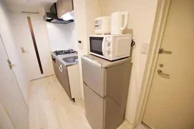 a small kitchen with a microwave on top of a refrigerator at Prime Stage Otsuka Ikebukuro P203 in Tokyo