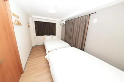 two beds in a small room with a window at Shinjuku NY House 2 in Tokyo