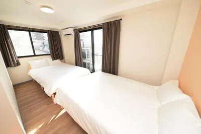 two beds in a room with windows at Shinjuku NY House 2 in Tokyo