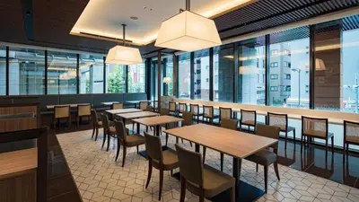 a restaurant with wooden tables and chairs and windows at Via Inn Prime Nihonbashi Ningyocho in Tokyo
